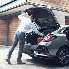 Muž otvírající zezadu zavazadlový prostor modelu Honda Civic 5D
