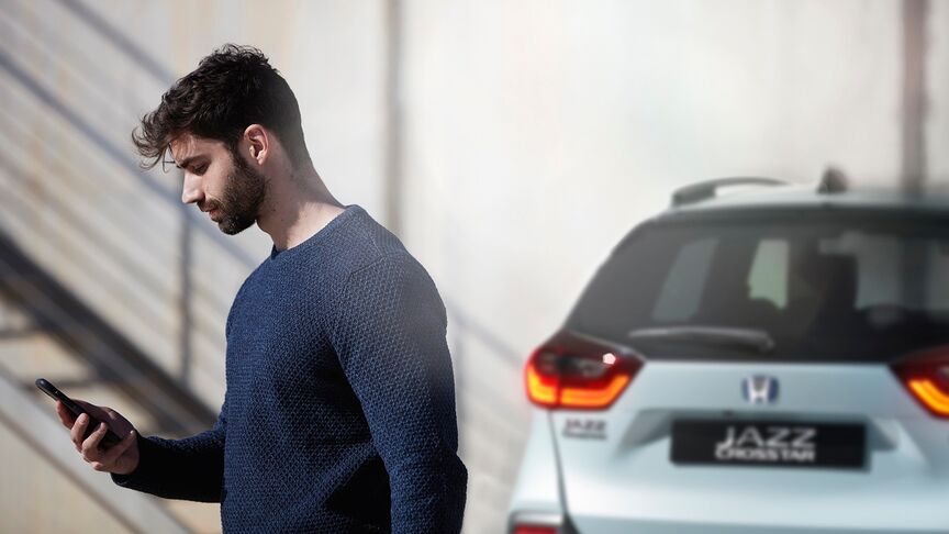 Dáma stojící vedle bílého vozidla Honda e používající aplikaci My Honda+