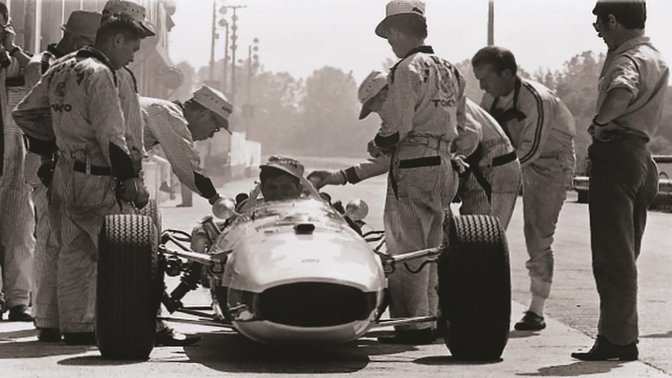 Pohled zepředu na vůz Honda Formule 1 ze 60. let s jezdcem a mechaniky