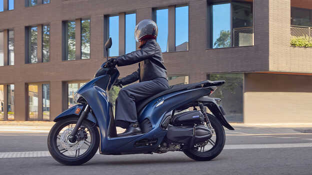 Boční pohled na jezdce na skútru Honda SH350 ve městě